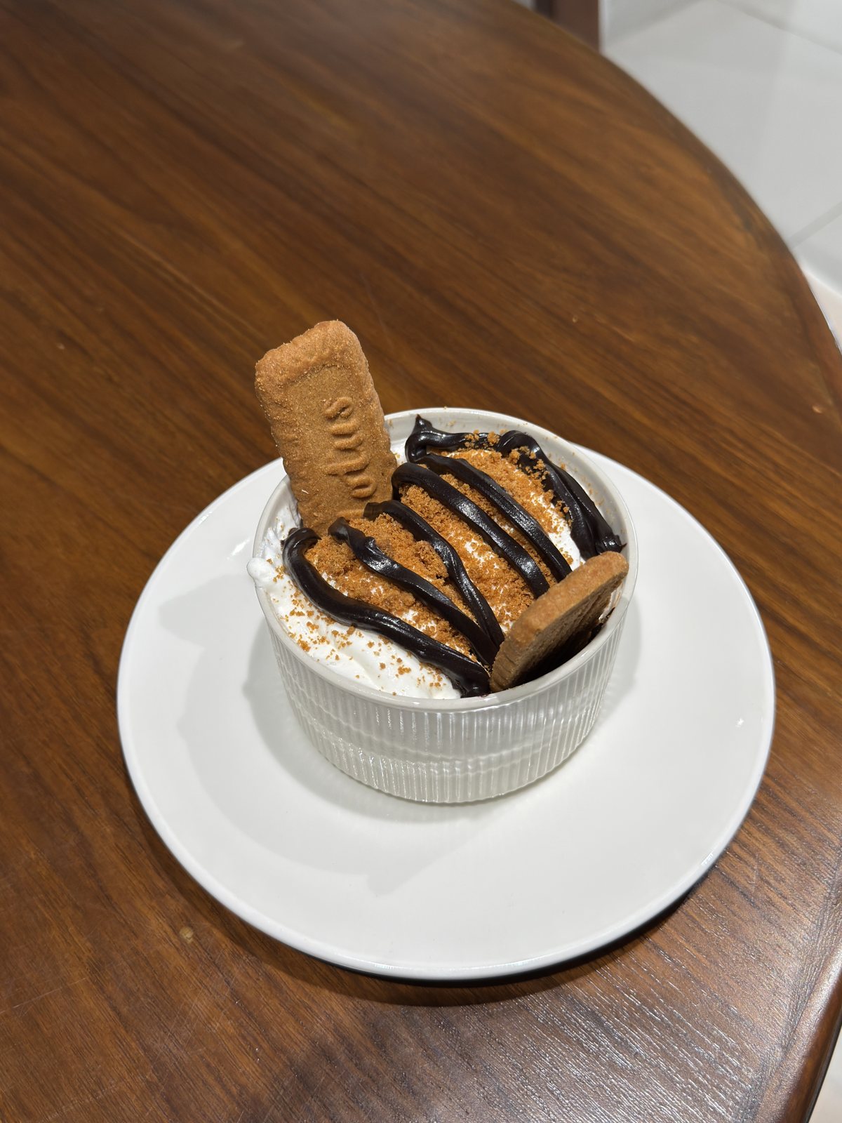 Biscoff ice cream dessert with chocolate drizzle and a biscuit on top